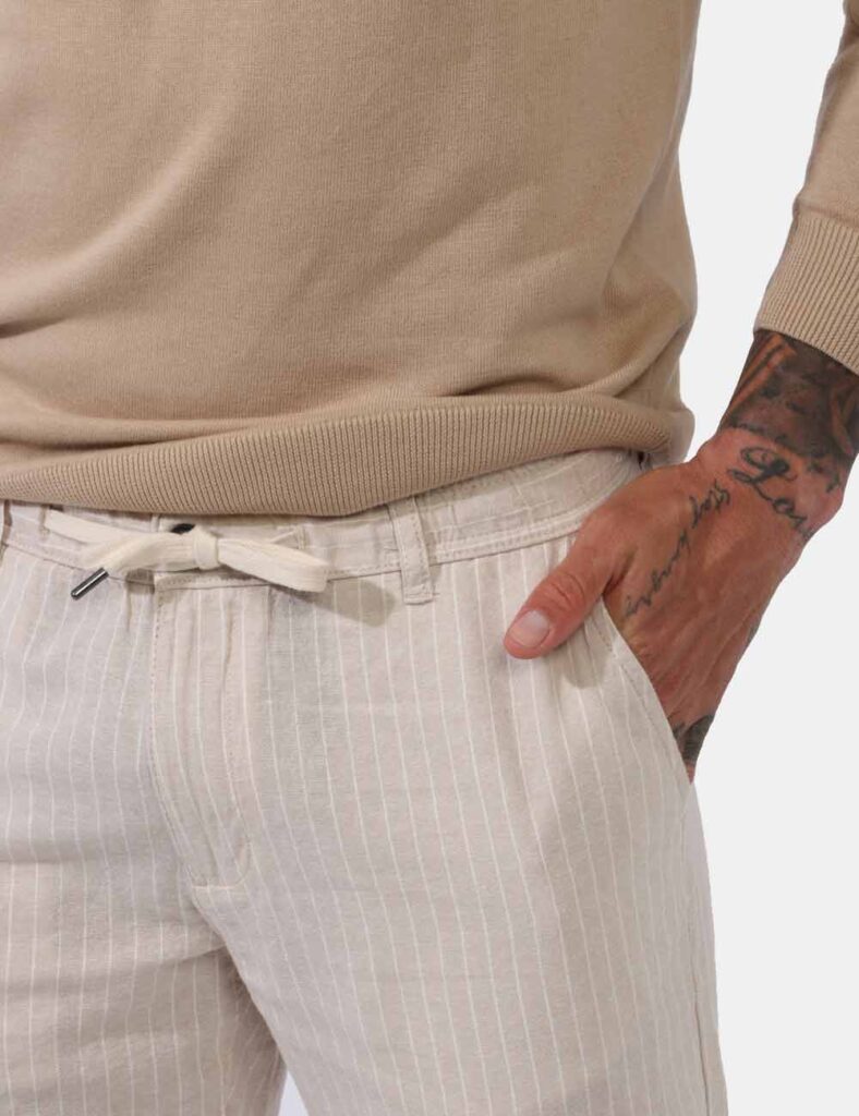 Pantaloni Goha Beige - Pantaloni leggeri su base beige ma rigato bianco. Presenti tasche a taglio trasversale sul fronte e