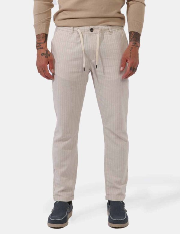 Pantaloni Goha Beige - Pantaloni leggeri su base beige ma rigato bianco. Presenti tasche a taglio trasversale sul fronte e