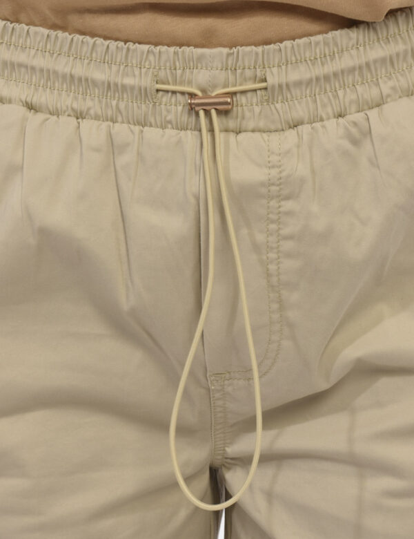 Shorts Yes Zee Beige - Shorts beige con coulisse in vita. Dettaglio fiore applicato sul finaco destro e medaglietta logo sul