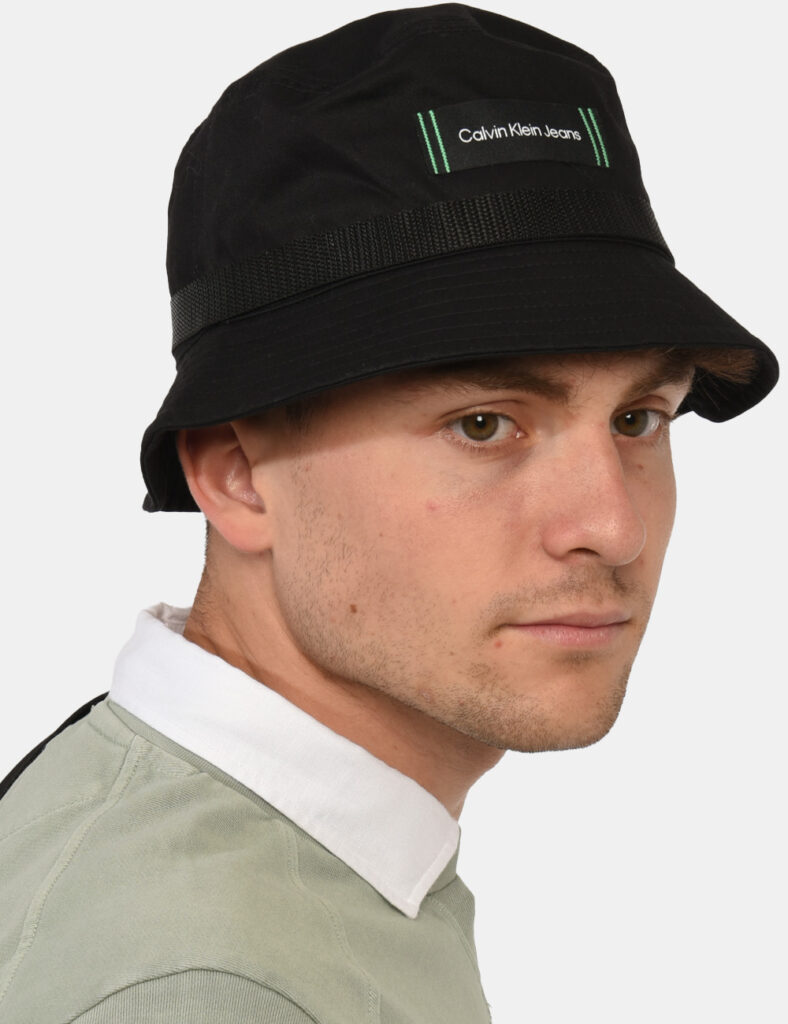 Cappello Calvin Klein Nero - Cappello modello 'alla pescatore' in total nero con patch logo brand verde. La vestibilità è mo