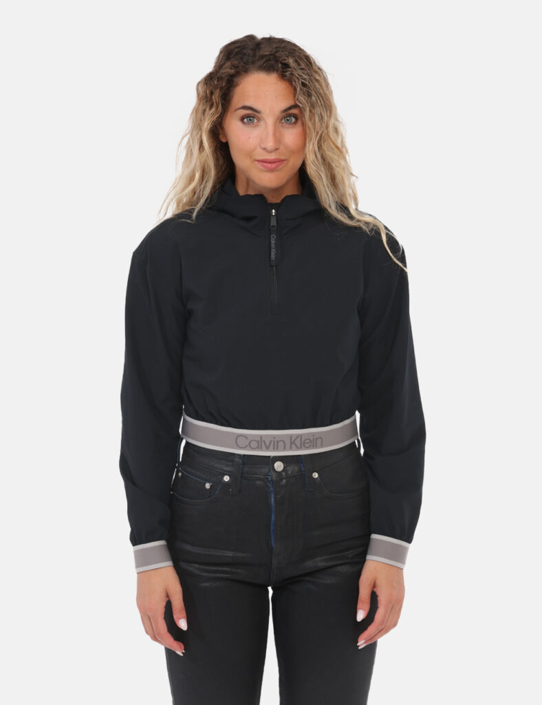 Giacca Calvin Klein Nero - Giacca a vento corta con cappuccio e zip. Presenta polsini e borso inferiore con logo Calvin Klei