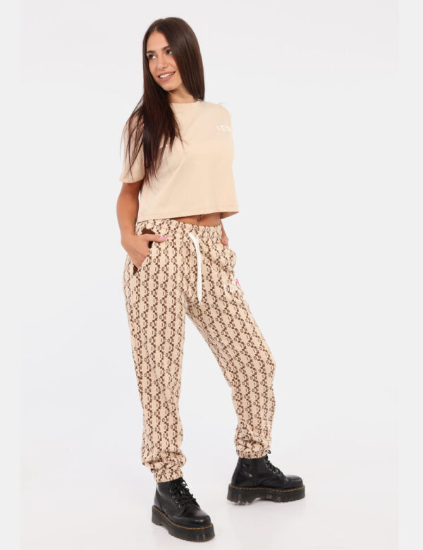 Pantaloni Icon Beige - Pantaloni simil tuta su base beige con logo brand stampa allover in marrone. Presenti tasche a taglio