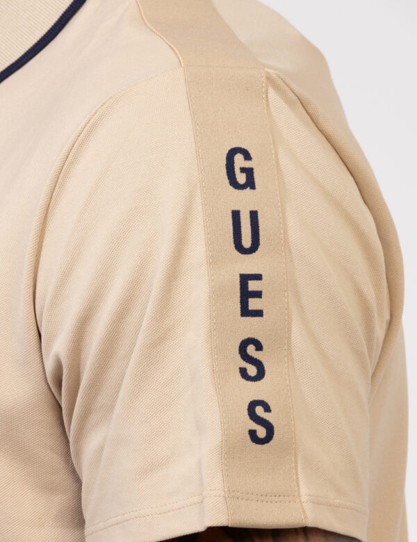 Polo Guess Beige - Polo in total beige con patch logo brand in tinta sulla manica. La vestiibilità è morbida e pratica grazi