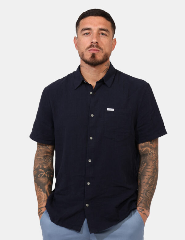 Camicia Guess Blu - Camicia a maniche corte, in misto lino/cotone, ed in total blu navy. Presente taschino a toppa. La vesti