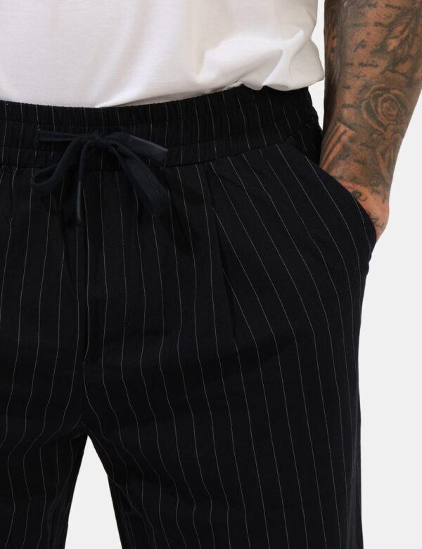 Pantaloni Goha Blu - Pantaloni gessati in total blu navy e righine bianche con tasche a taglio trasversale. La vestibilità è